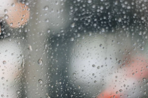 Verschwommenes Regenfenster mit rotem Bokeh-Licht — Stockfoto