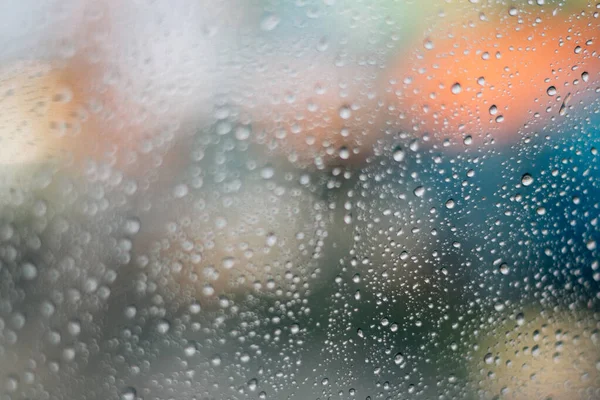 Verschwommenes Regenfenster mit rotem Bokeh-Licht — Stockfoto