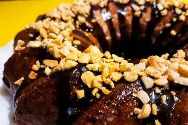 Çukulata kaplı yuvarlak turta, kıyılmış fıstıkla süslenmiş.