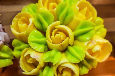 Ahşap arka planda kremadan renkli laleler olan kekler.