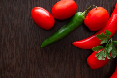 Koyu ahşap arka planda acı biber ve domates.