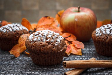 Sonbahar yaprakları ve tarçın arka planında elmalı çikolatalı kekler.