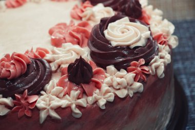 Koyu arkaplanda krema çiçekleri olan pembe pasta.