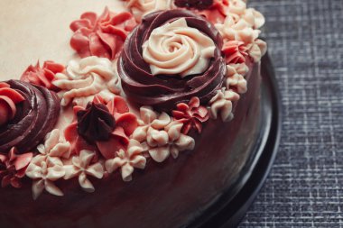 Koyu arkaplanda krema çiçekleri olan pembe pasta.