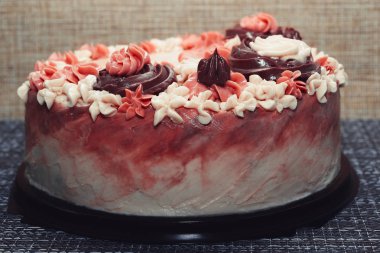 Koyu arkaplanda krema çiçekleri olan pembe pasta.