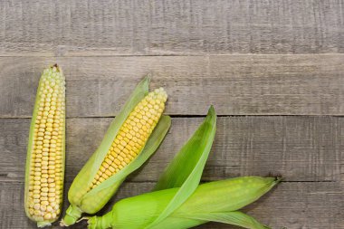 Tahta arka planda taze sarı mısır.