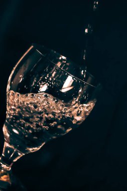 Siyah arka planda bir bardak, sıçramış bardakta bir zeytin damlası.