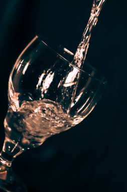 Siyah arka planda bir bardak, sıçramış bardakta bir zeytin damlası.