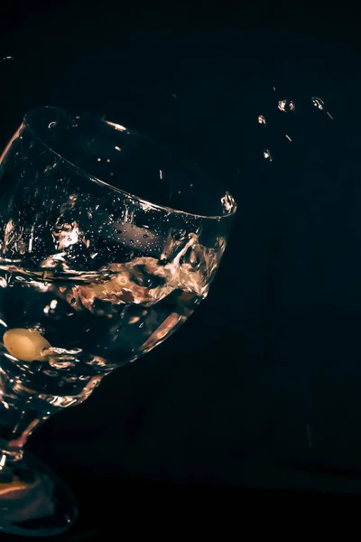黑色底座上的杯子里的橄榄滴在水花斑斑的杯子里 — 图库照片