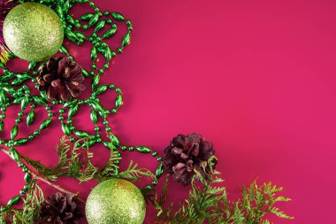 Noel süsleri, koniler, Noel topları ve pembe arka planda dallar. Güzel bir tatil için Aroma mumu. Metnin için yer.