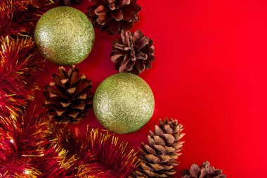 Tasarım ve tebrik kartları için kırmızı arka planda koni ve Noel toplarının şenlikli kompozisyonu. Metin için yer.