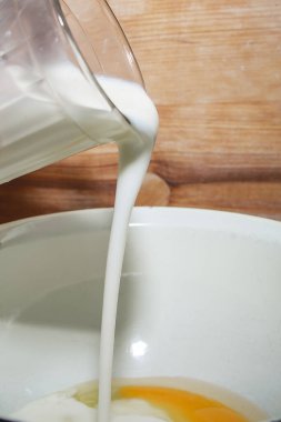 Yemek pişirme süreci. Aşçı hamura süt döker. Ev yapımı konsept.