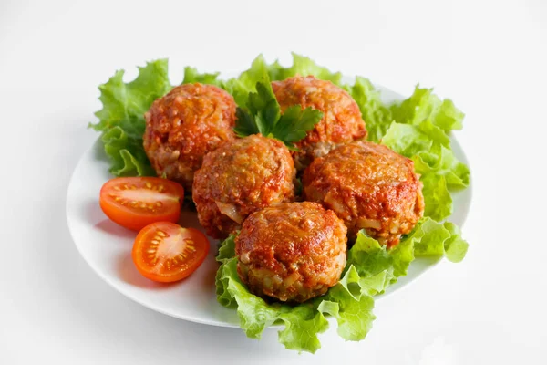 Meat balls in tomato sauce with vegetables isolated on a white background.