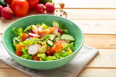 Domatesli, salatalı ve turplu sebze salatası tarifi. Ahşap arka planda mevsimlik bir tabak. Diyet için vejetaryen yemeği. Metin için yer.