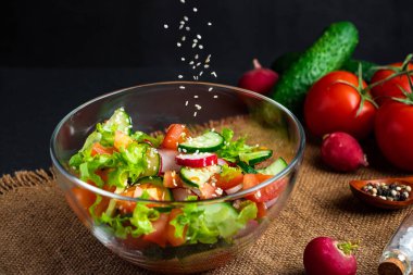 Sebze salatası hazırlama süreci. Mevsimlik yaz yemekleri, siyah arka planda vejetaryen yemekleri..