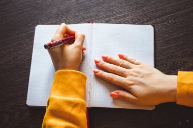 Genç bir kadın sol elinde bir kalem tutuyor ve boş bir not defterine bir not yazıyor. Uluslararası Solaklar Günü