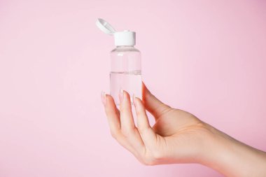 Pembe arka planda krem şişesi olan kadın elleri. Spa ve vücut bakımı konsepti. Reklam için görüntü.