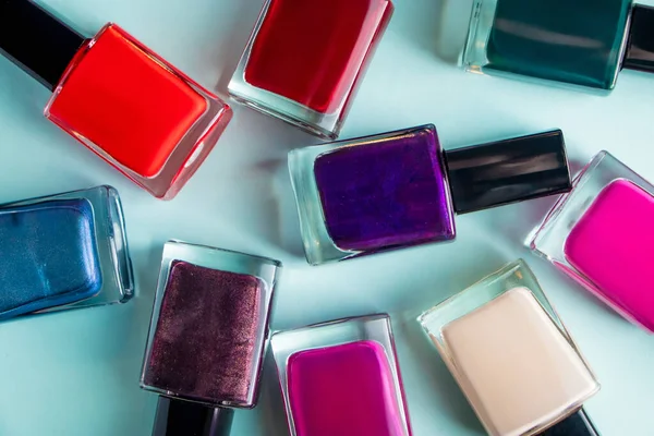 Group of bright colored nail polishes on a blue background. Set of decorative cosmetics for body care.