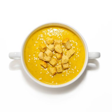 Beyaz arka planda izole edilmiş balkabağı kremalı çorba. Beyaz arka planda izole edilmiş beyaz bir bulyon içinde beyaz kraker ve susam tohumlu balkabağı kreması çorbası.