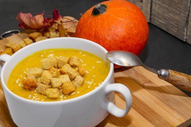 Ahşap zemin üzerinde susam tohumları olan sonbahar balkabağı çorbası. Sonbahar kabağı çorbası. Kraker ve susam tohumlu çorba.