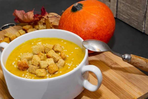 Ahşap zemin üzerinde susam tohumları olan sonbahar balkabağı çorbası. Sonbahar kabağı çorbası. Kraker ve susam tohumlu çorba.