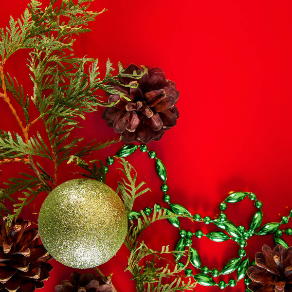 Праздничная композиция конусов и рождественских шаров на красном фоне для оформления и поздравительных открыток.