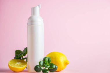 Limon yağlı organik kozmetik ürünler. Pembe arka planda narenciyeli bir şişe nemlendirici. Metin için yer.