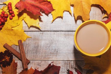 Sütlü ve sarı yapraklı bir fincan kahve. Sonbahar tasarımı için rahat kompozisyon. 