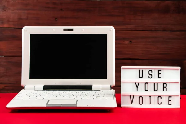 Online voting. Laptop and notepad on a red background. Election concept, place for text.