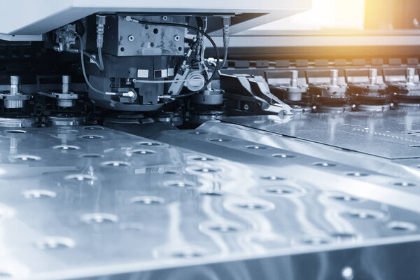 Close-up of the CNC punching machine in the light blue scene.High technology metal forming process.