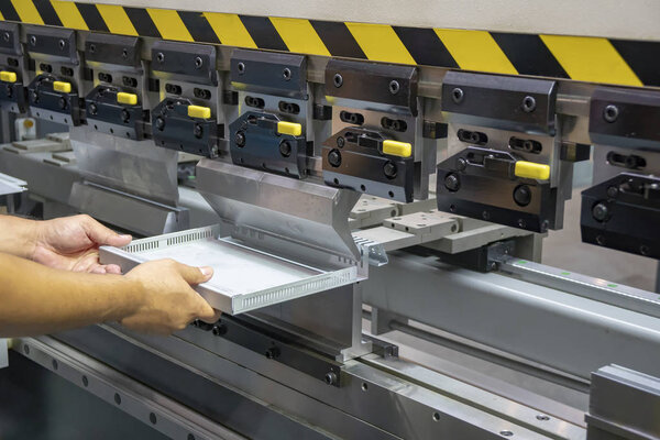 Техник-оператор передает часть листового металла гидравлическим станком для гибки. Концепция обработки металла
