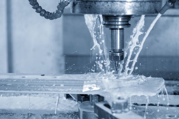 The CNC milling machine cutting the part using  the coolant  with the light blue scene