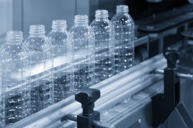 Konveyör bant ışık mavi sahne içki fabrikasında yeni plastik şişelerde. İçme suyu üretim süreci.