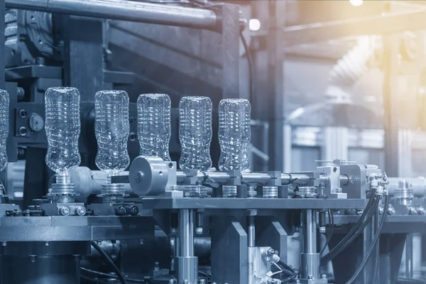 The  plastic bottles manufacturing process at the drinking factory in the light blue scene. Drinking water manufacturing process.