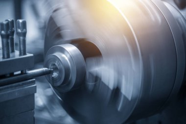 Torna makinesi ışık mavi sahnede çelik şaft kesme işlemi.