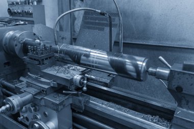 Torna makinesi soğutucu akışkan ile ışık mavi sahnesinde çelik şaft kesme işlemi.