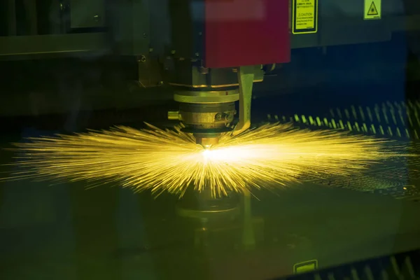 The CNC fiber laser cutting machine cutting the sheet metal plate  with the sparking light. Modern sheet metal manufacturing process.