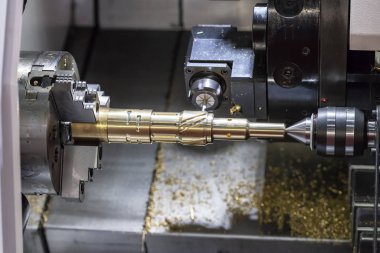 The CNC lathe machine cutting  the slot groove at the brass shaft .Hi-technology automotive part manufacturing process. clipart