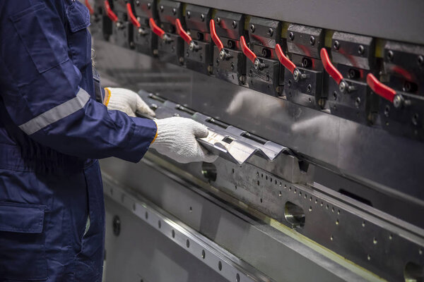 Техник использует гидравлический станок для гибки. Процесс производства листового металла
.