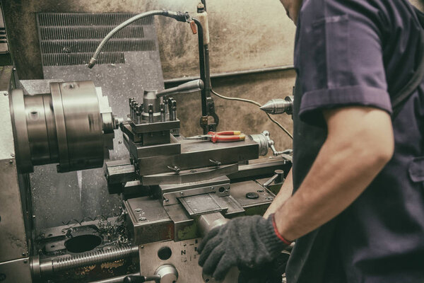 The skill operator working with lathe machine in vintage scene.