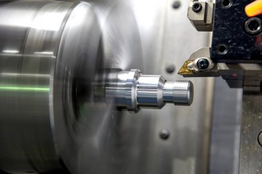 The CNC lathe machine cutting the thread    at the metal parts.  clipart