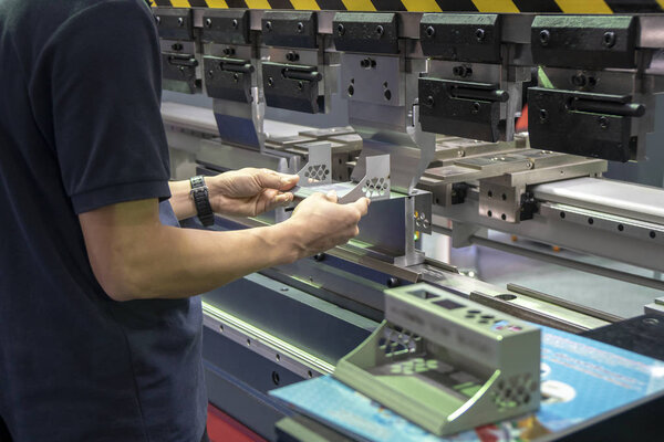 Техник использует гидравлический станок для гибки.