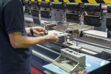 Hidrolik bükme makinesi ile çalışan operatör. 