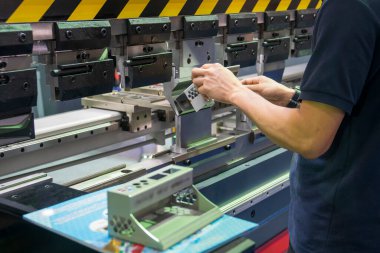 Teknisyenle hidrolik bükme makinesi operasyonu. Teknisyen ile bükme makinesi tarafından üretilen otomotiv levhası metal üretim süreci.