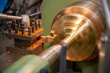 Torna makinesi, pirinç şaft parçalarını kesme aletleriyle kesiyor. Makineyi döndürerek metal işleme süreci.