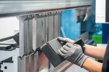 Hidrolik bükme makinesiyle çalışan metal işçisi. Teknisyen ile bükme makinesi tarafından üretilen otomotiv levhası metal üretim süreci.