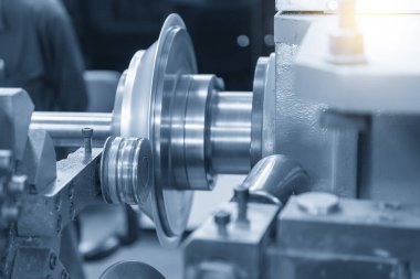 Açık mavi sahnede torna makinesiyle metal dönme işlemini kapat. Metal dönüş metoduyla metal oluşum süreci.