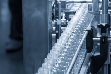 Açık mavi sahneyi doldurmak için konveyör bandındaki boş içme suyu şişeleri. İçme suyu üretim sürecinin yüksek teknolojisi.