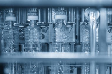 Taşıyıcı banttaki boş su şişeleri mavi ton sahnesini doldurmak için. İçme suyu üretim sürecinin yüksek teknolojisi. 