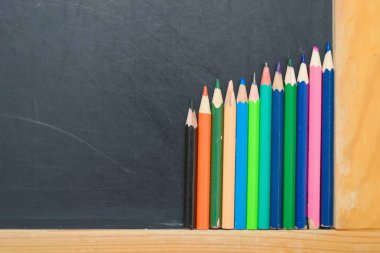 Bir kara tahta üzerinde renkli kalemler. Okul kavramı
